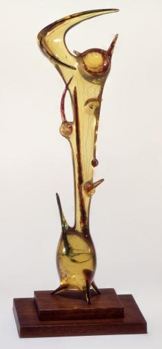 Vertically-oriented abstract sculpture with various elements encased in light yellow resin
