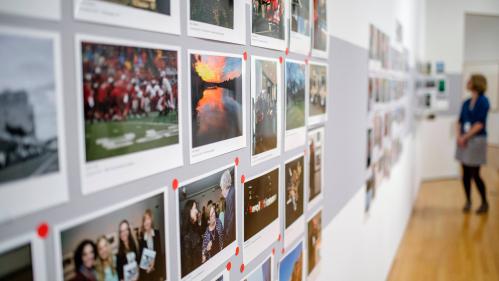 Wall of taped photographs with viewer at far right