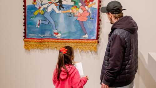 A girl and her father look at a work of art depicting a figure skating scene