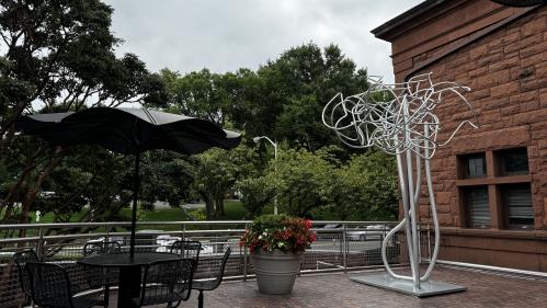 outdoor terrace with picnic table and sculpture next to a brown building