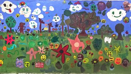 Mural painted by kids of blue sky and green grass filled with various emojis
