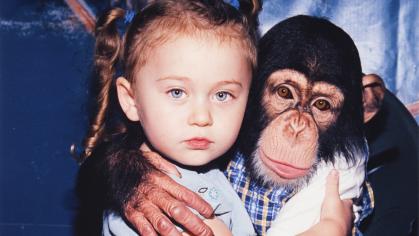 seated young girl and chimp embracing