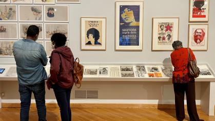 Three people look at drawings and posters in the Angela Davis exhibition