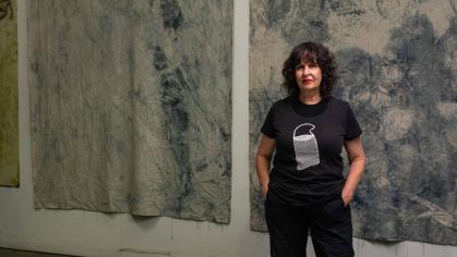 photo of a white woman with dark hair standing in front of paintings