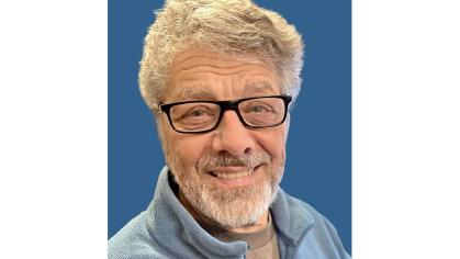 headshot of a white man with black glasses and light hair, beard, mustache