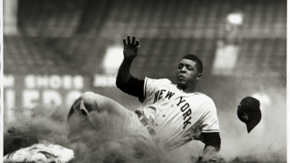 Baseball player, Willie Mays, slides into a base.
