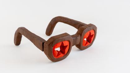 Carved glasses made from wood with each "lens" painted red with a star shape cut-out