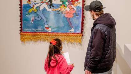 A girl and her father look at a work of art depicting a figure skating scene