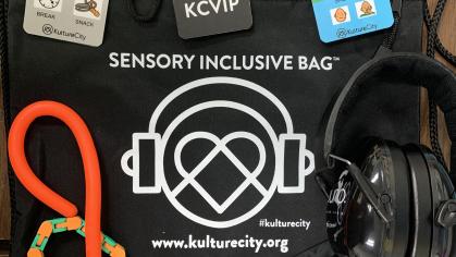 KultureCity bag with contents laid out: communication cards, headphones, therapeutic sensory devices