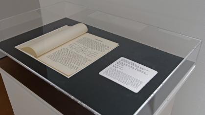 Gallery view of exhibition; typewritten text on paper displayed in vitrine