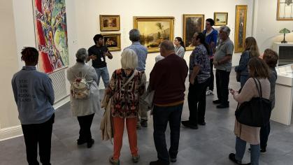 group of people in gallery looking at art and listening to a tour guide