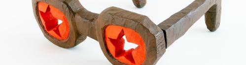 Carved and painted wooden glasses with brown frames and star cutouts in the red lenses