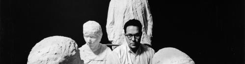 Black and white photo of George Segal seated with bus stop figures