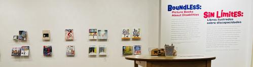 Table and chairs with books on holders mounted to a white wall.