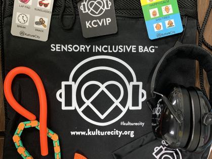 KultureCity bag with contents laid out: communication cards, headphones, therapeutic sensory devices
