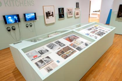 Overhead gallery view focusing on large four-part case displaying magazines and other documents