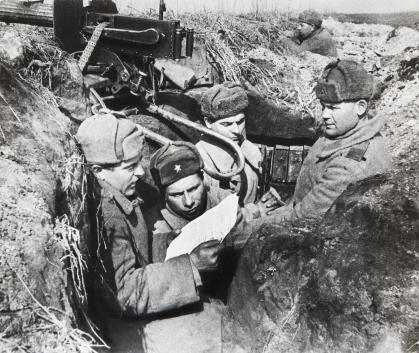 Photo of Russian soldiers in a trench reading a set of papers