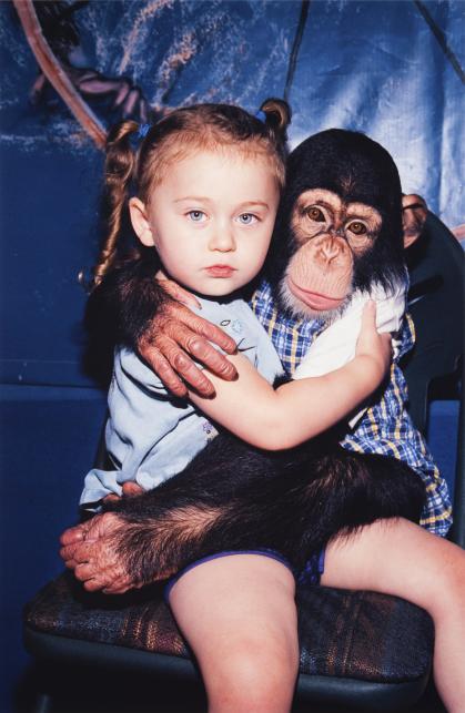 seated young girl and chimp embracing