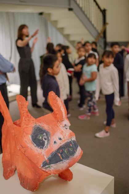 Sculpture of red dog in foreground with group of students visible in background