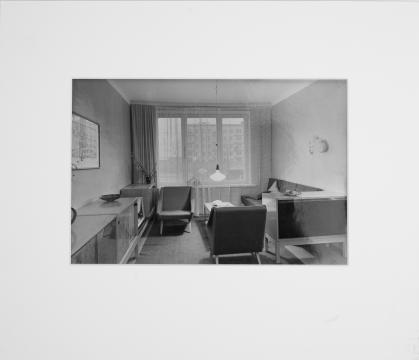 Black and white photo of Soviet apartment living room with armchairs, couch, and cabinets