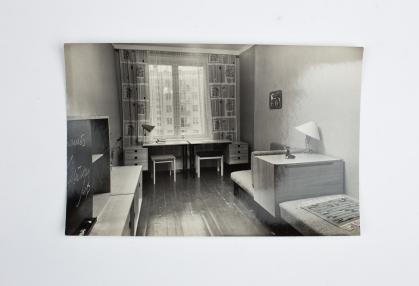 Black and white photo of Soviet apartment room showing desk, cabinets, and bench seating