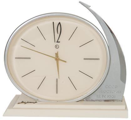 Table clock with oval face and silver arc design on right side, like a rocket in orbit