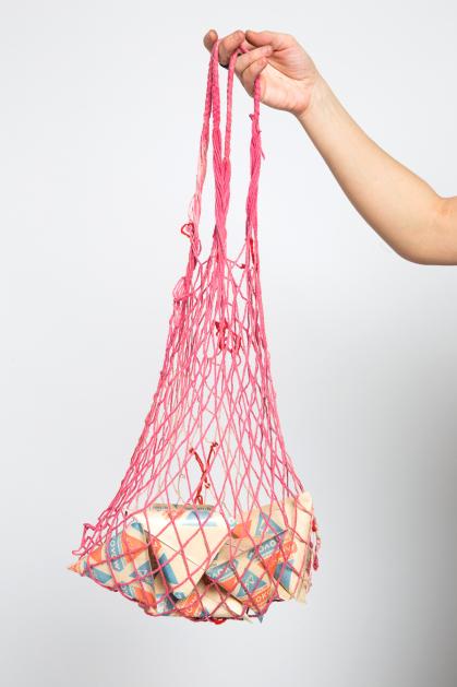 Arm lifting up pink mesh net bag holding packages