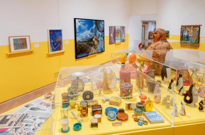 Installation view of Everyday Soviet with case of household objects and art on the walls