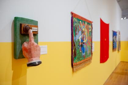 Gallery view of Everyday Soviet exhibition; carved sculpture of hand pressing doorbell is in focus