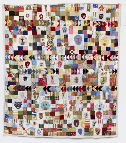 Mutlicolored quilt with mask-like faces interspersed with squares and triangles