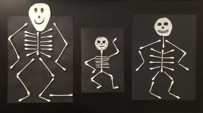 3 skeletons made of white cotton swabs and white paper on black background