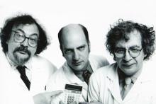 three white middle aged men in lab coats stare at the camera