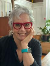 headshot of white woman with short silver hair and red glasses, smiling