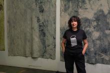 photo of a white woman with dark hair standing in front of paintings 