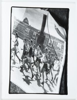Photo of men running a race past a Soviet government building with large posters of officials