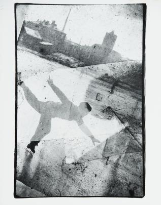 Photo of a boy figure skating in a city seen through broken, speckled glass
