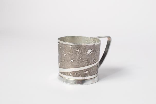Silver-colored handled cup with decoration of stars and planets