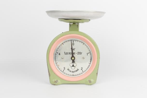 Kitchen scale with silver tray, light green body, and pink trim around the dial