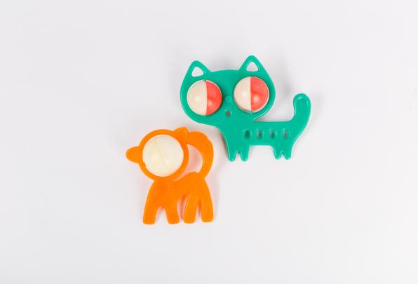 Two plastic baby rattles; one is orange and shaped like a monkey, the other is green and shaped like a cat