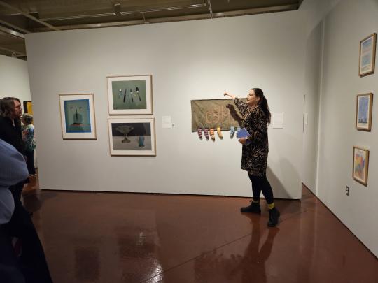 Tour guide stands in an art gallery speaking to a group.