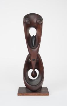 Dark wooden carved sculpture with triangular form on top of oval form. Both forms have holes.