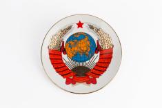 Porcelain plate with globe, hammer and sickle, rising sun, red star, bundles of wheat, and red ribbon