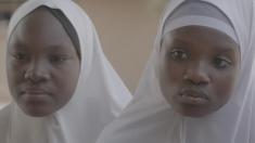 Photo of two young African women in white head coverings, seen from the neck up.